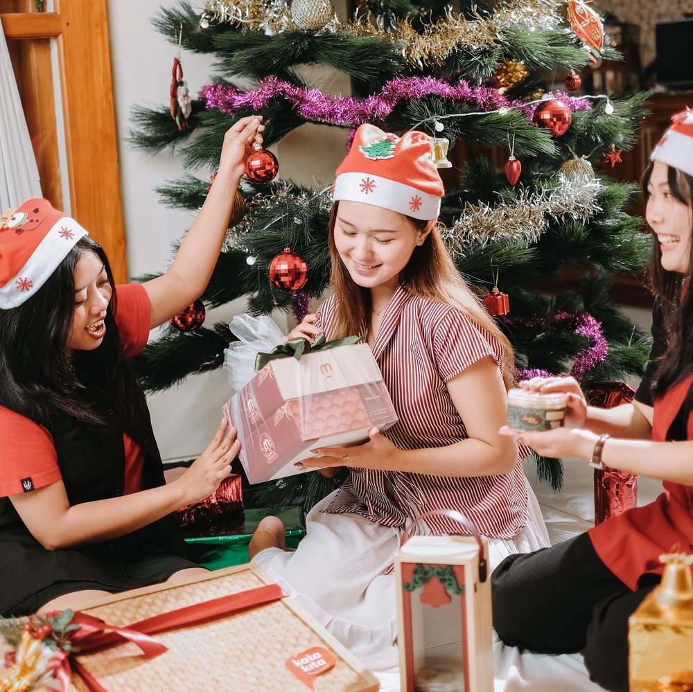 Friends unwrapping gifts by the Christmas tree