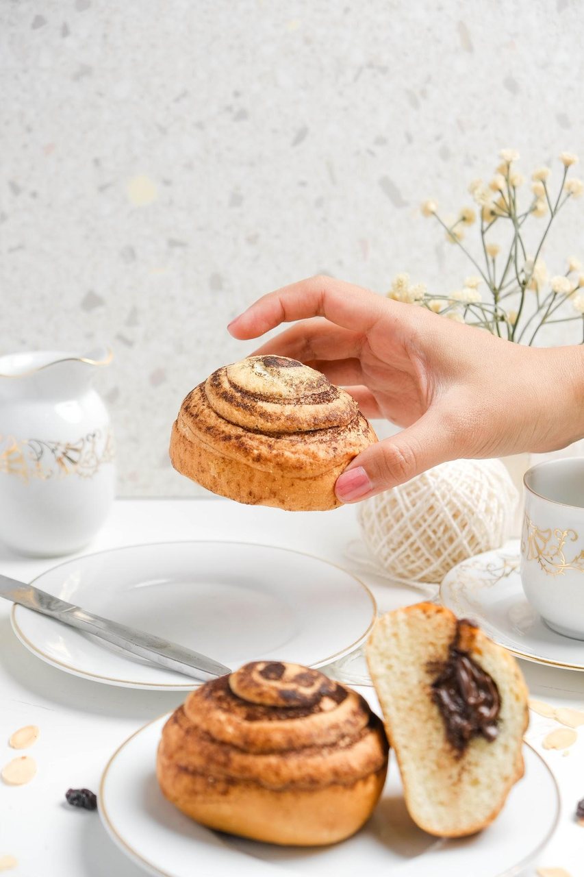 A hand reaching for a cinnamon bun, shot in natural light
